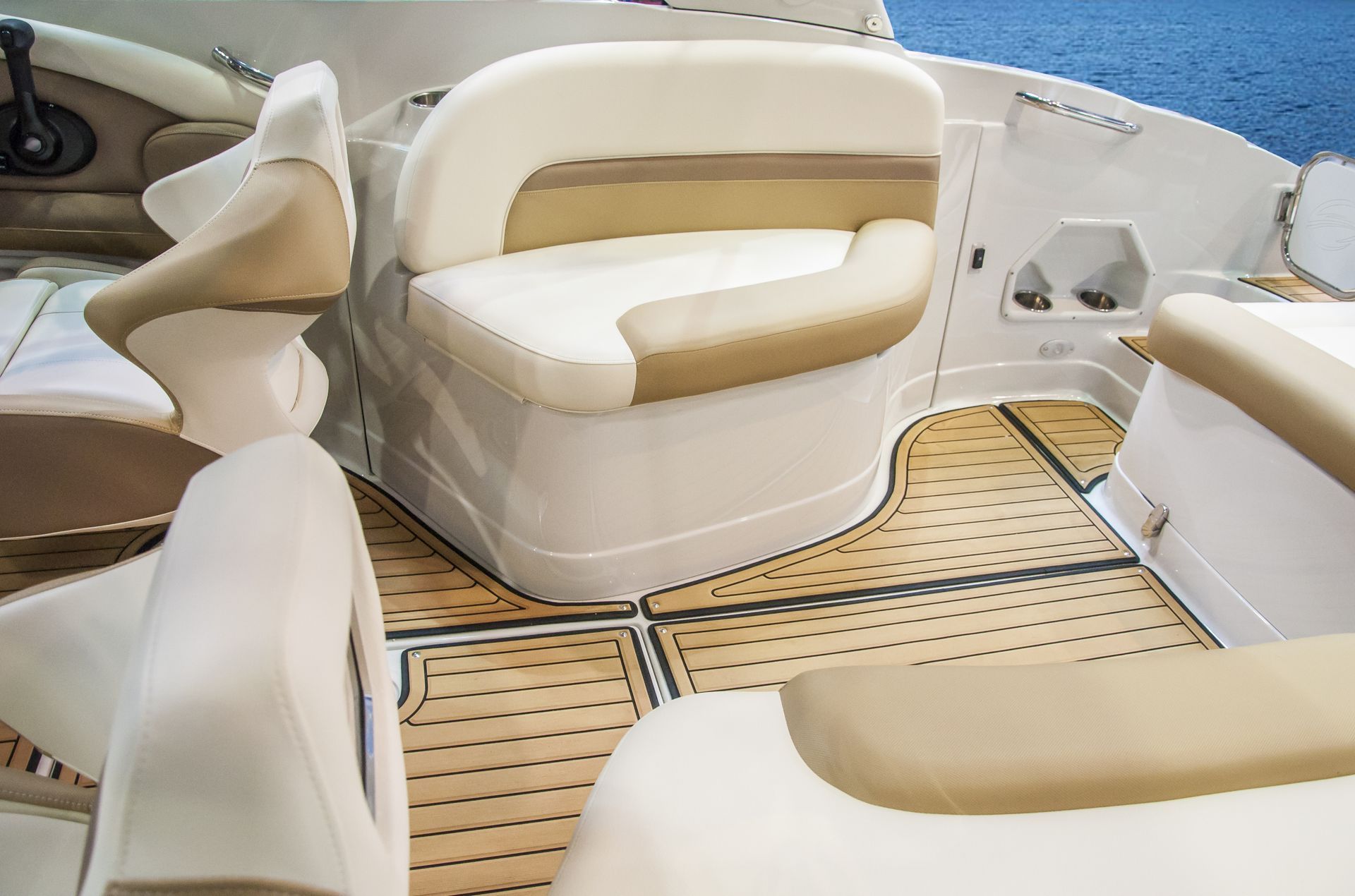 White and beige boat cockpit seating with tan teak-style deck flooring and curved benches
