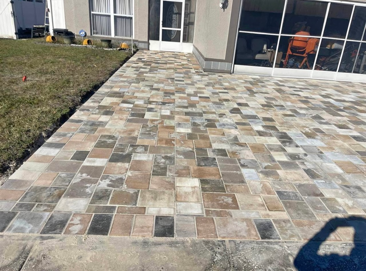 Brick patio with various colored pavers leading to a house entrance.