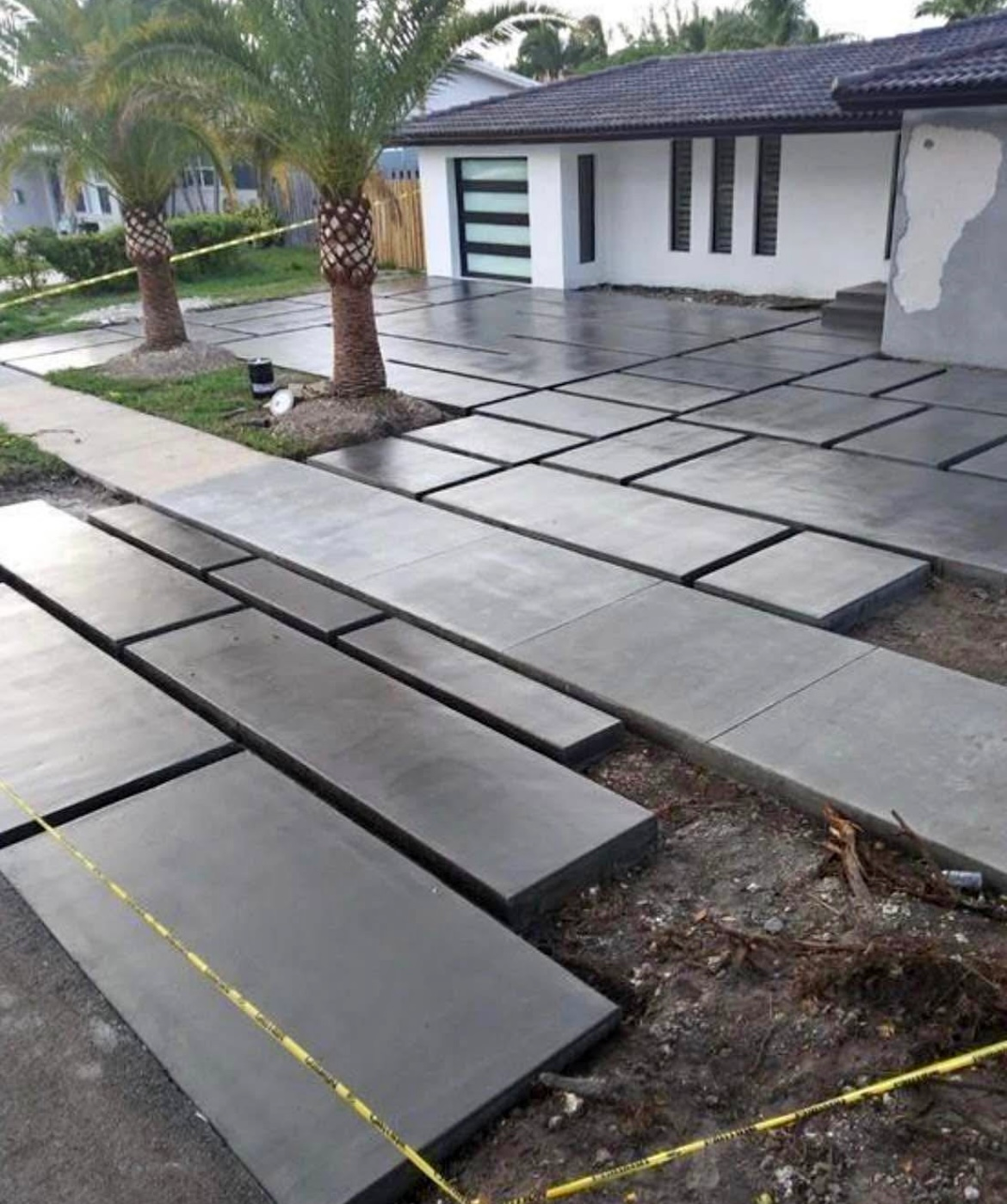 Concrete slabs laid out for a driveway and walkway in front of a modern house.
