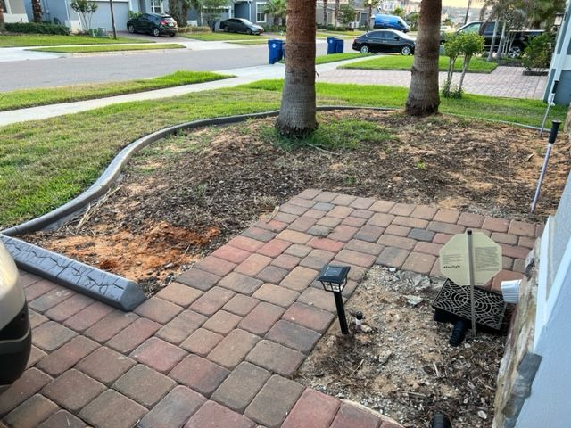 Brick walkway in front yard, with lawn, trees, and street in the background.