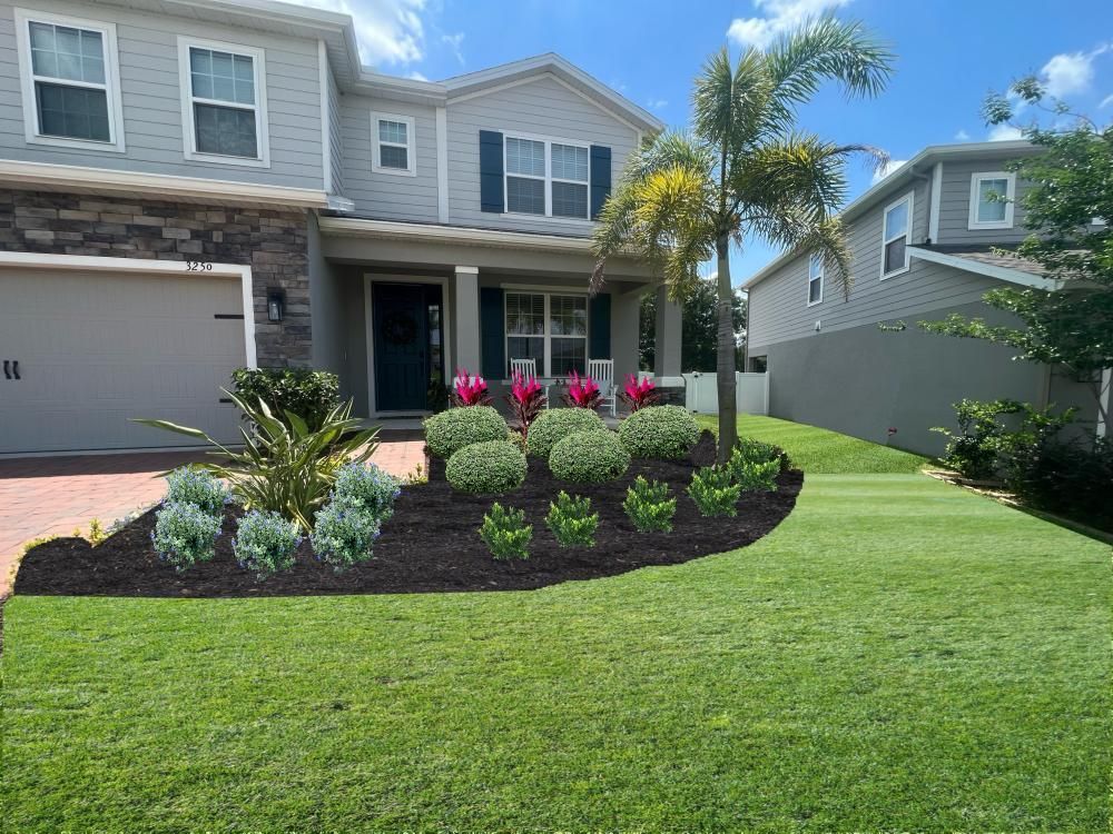 House exterior with manicured lawn and garden bed, blue sky.