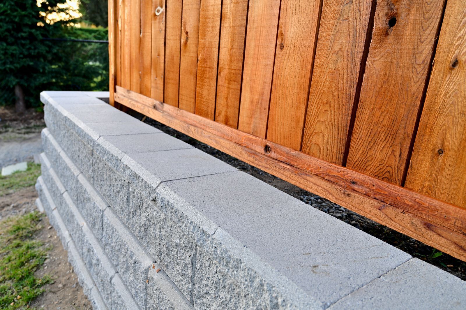 Stone retaining walls with plants and grass in a garden setting.