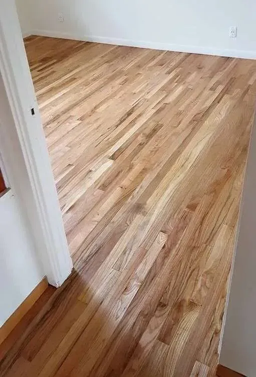 A room with a wooden floor and a white wall.