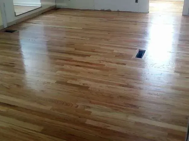 A living room with a wooden floor and a mirror.