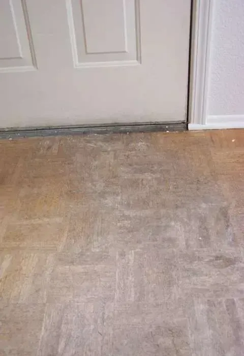 A close up of a wooden floor next to a door.