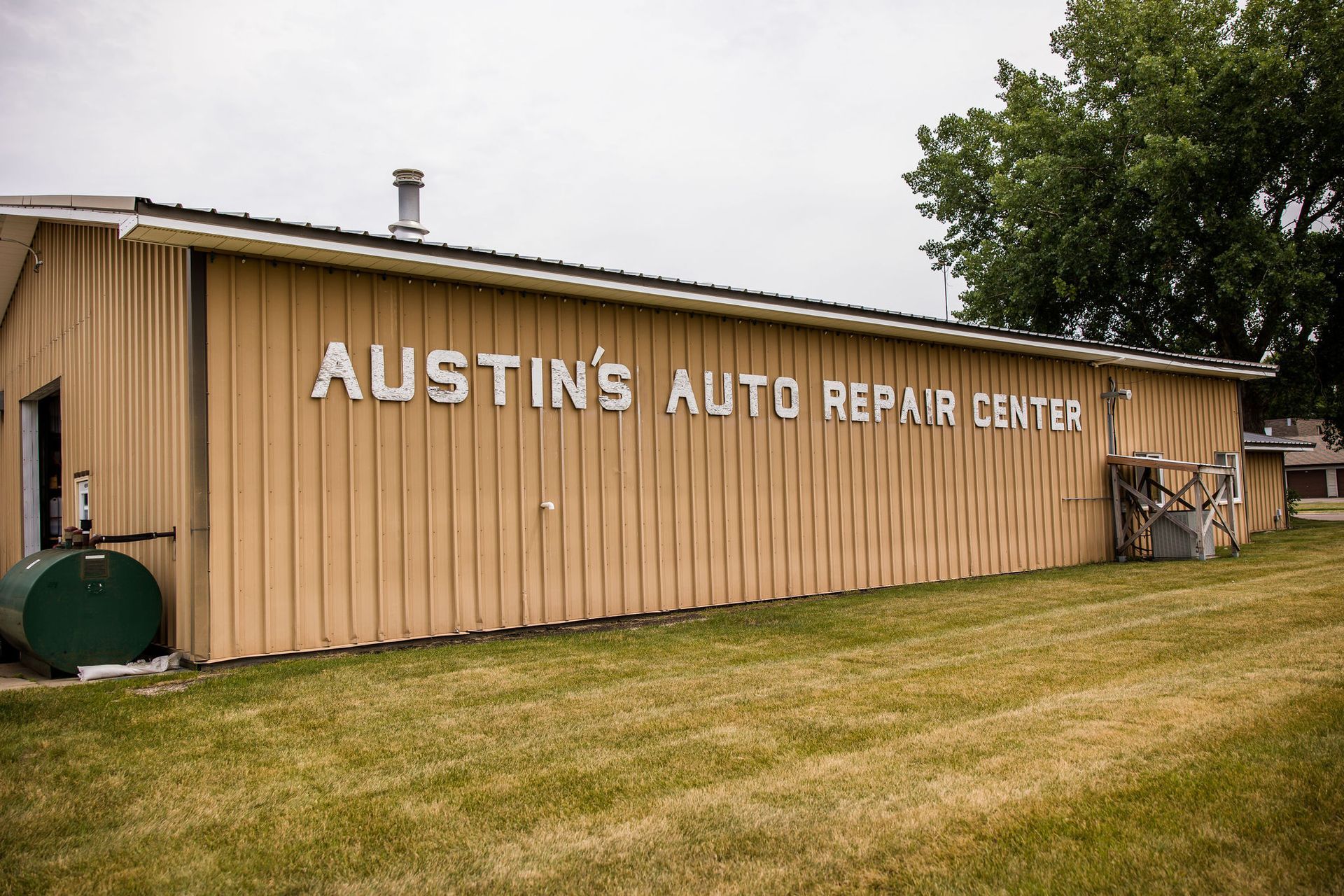 Austin's Auto Repair Center: A tan building with a sign on the front, green grass in front.