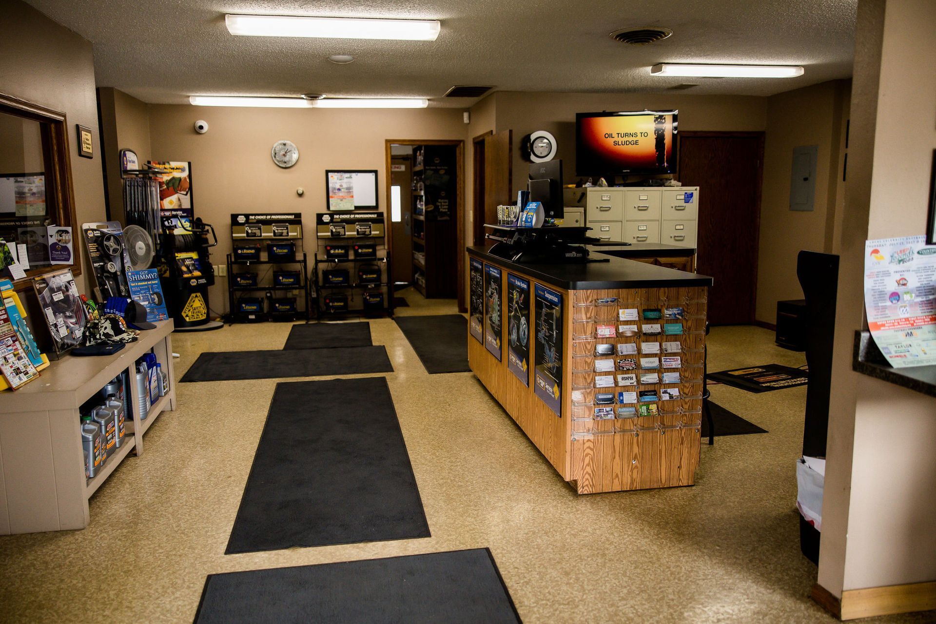 Interior of a store with a counter, merchandise displays, and a television. The floor is speckled with black mats.