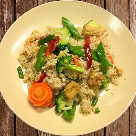 A white plate topped with rice and vegetables on a wooden table