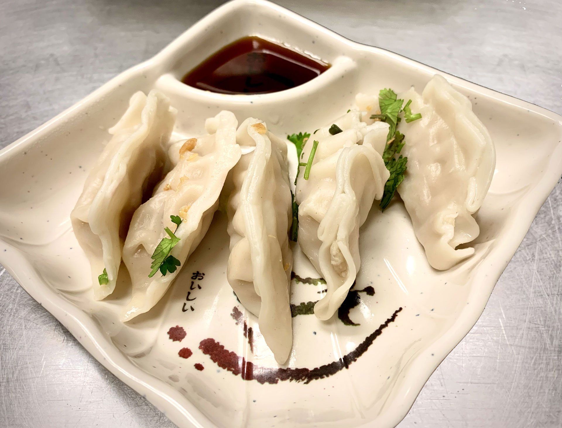 A white plate topped with dumplings and dipping sauce