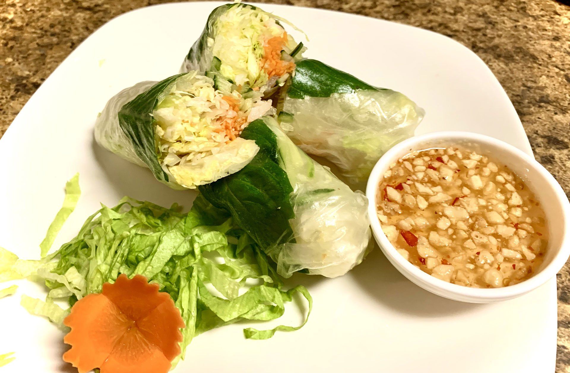 A white plate topped with vegetable rolls and a bowl of dipping sauce.