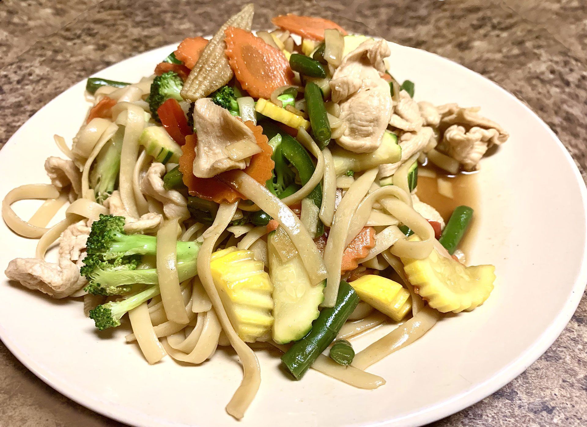 A white plate topped with noodles and vegetables on a table.