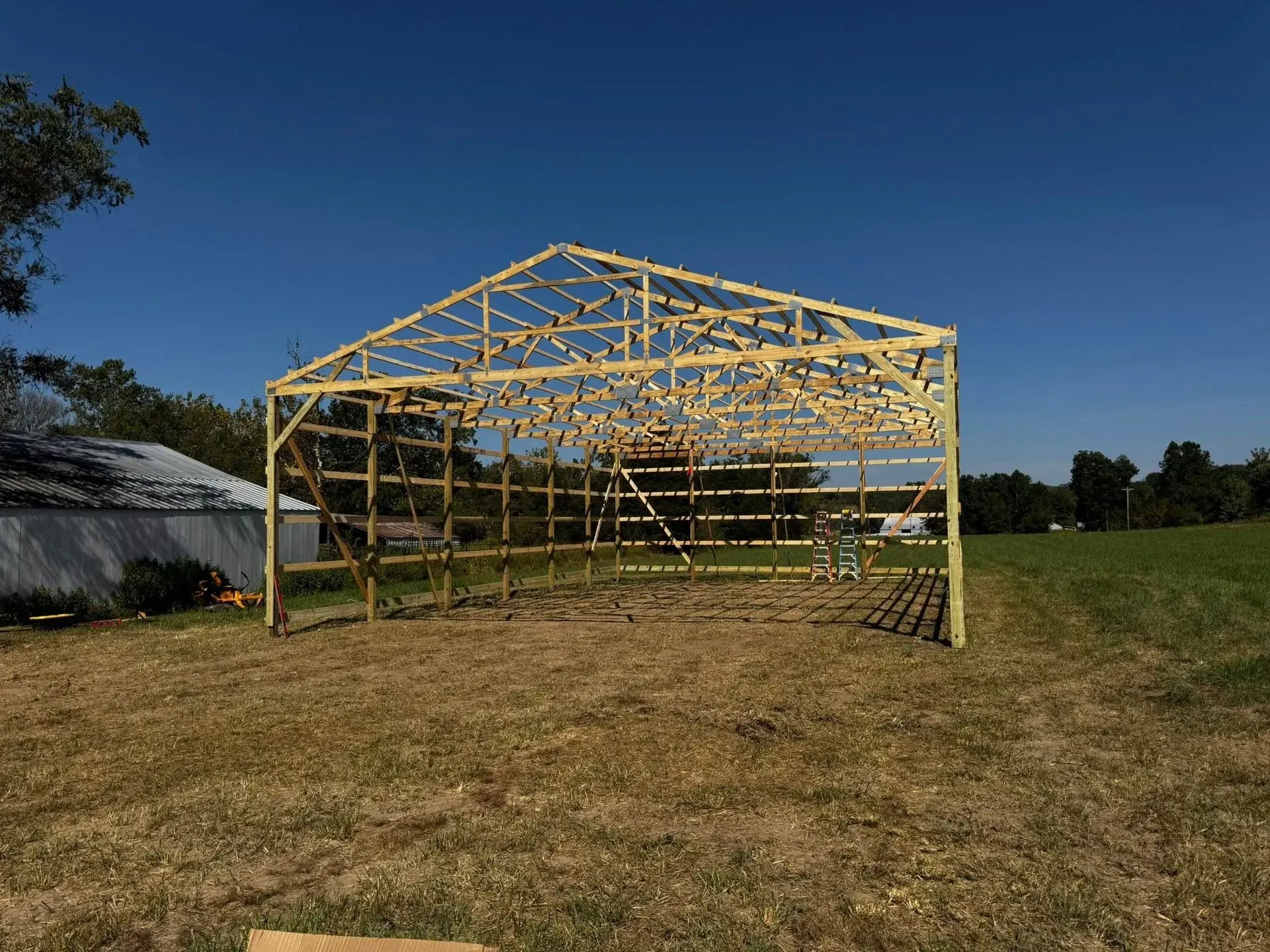 Yellow metal frame structure under construction on a grassy field beneath a clear blue sky