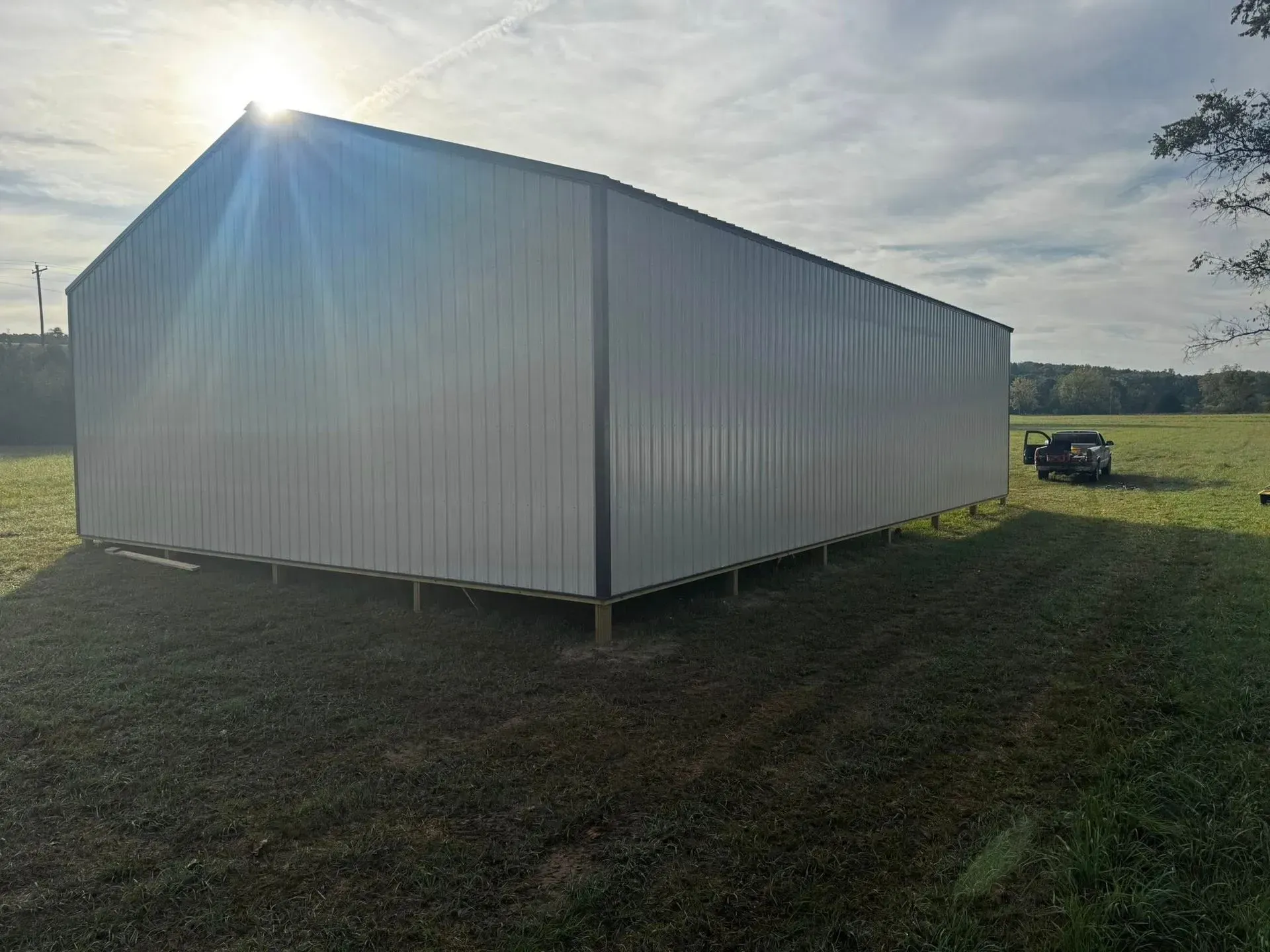 White metal shed in a grassy field under bright sunlight