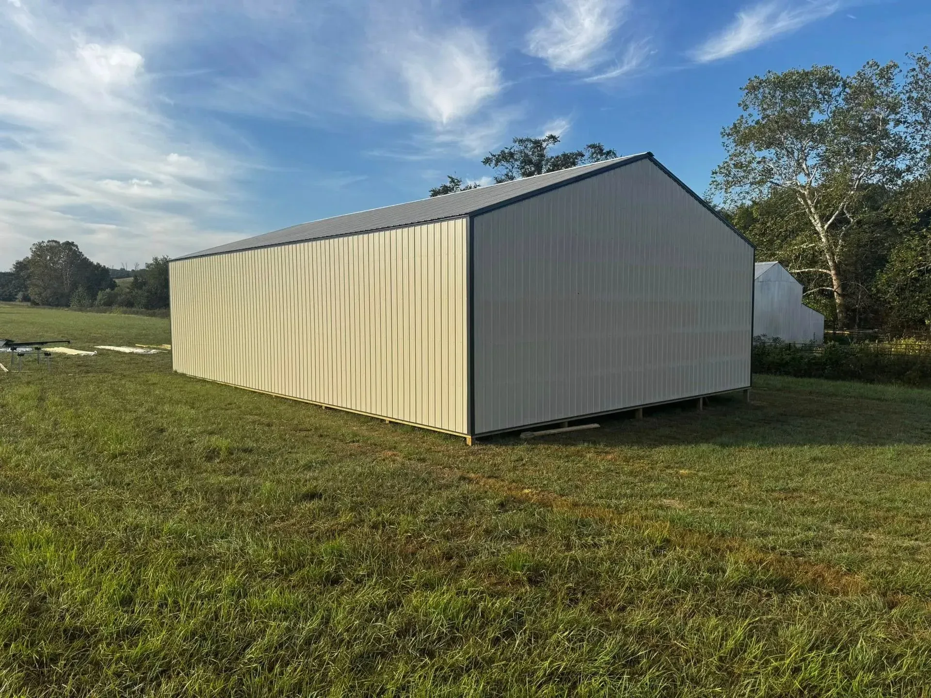 White metal shed in a grassy field under a blue sky.