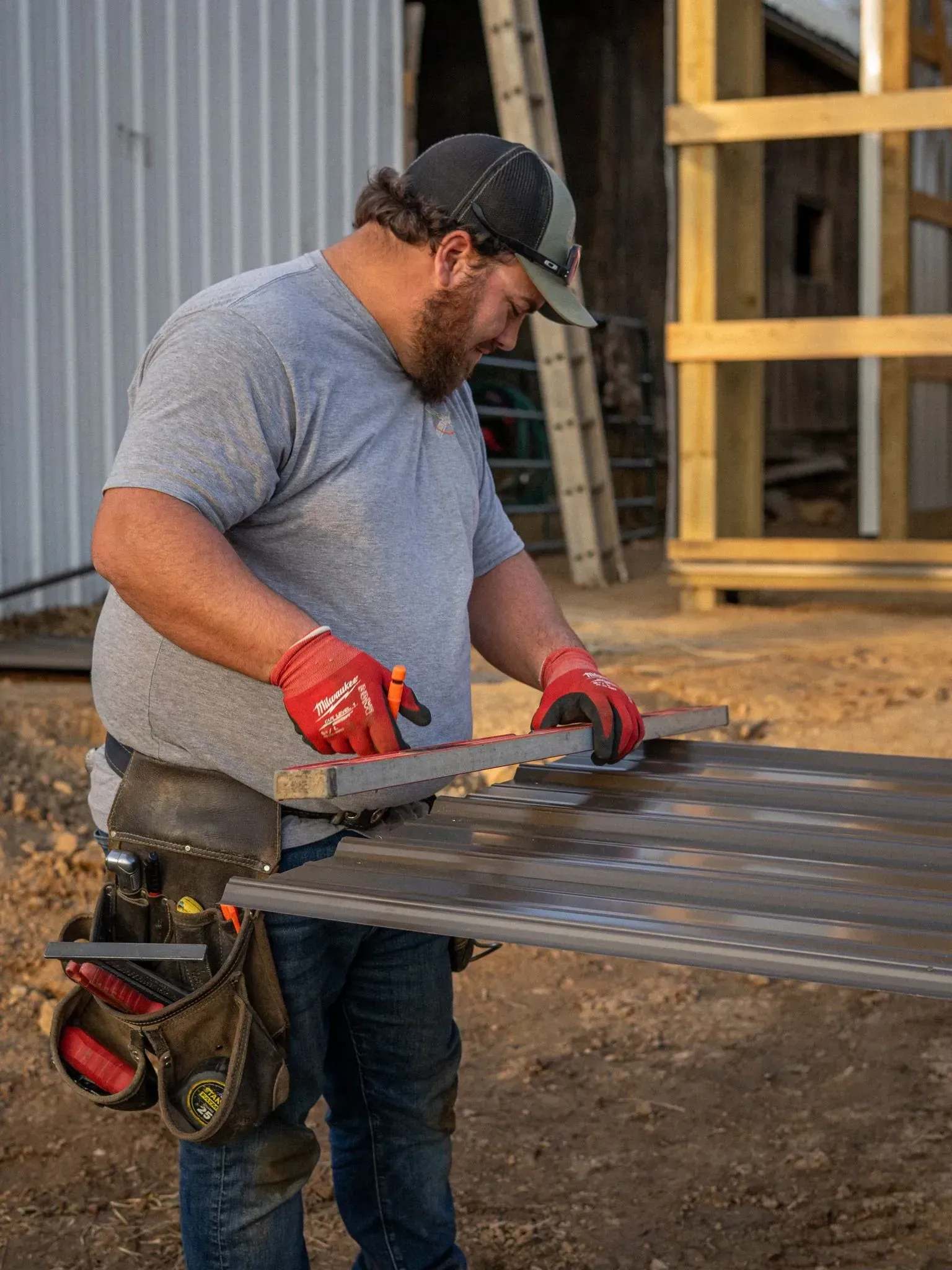 Worker in red gloves measuring metal siding at a construction site