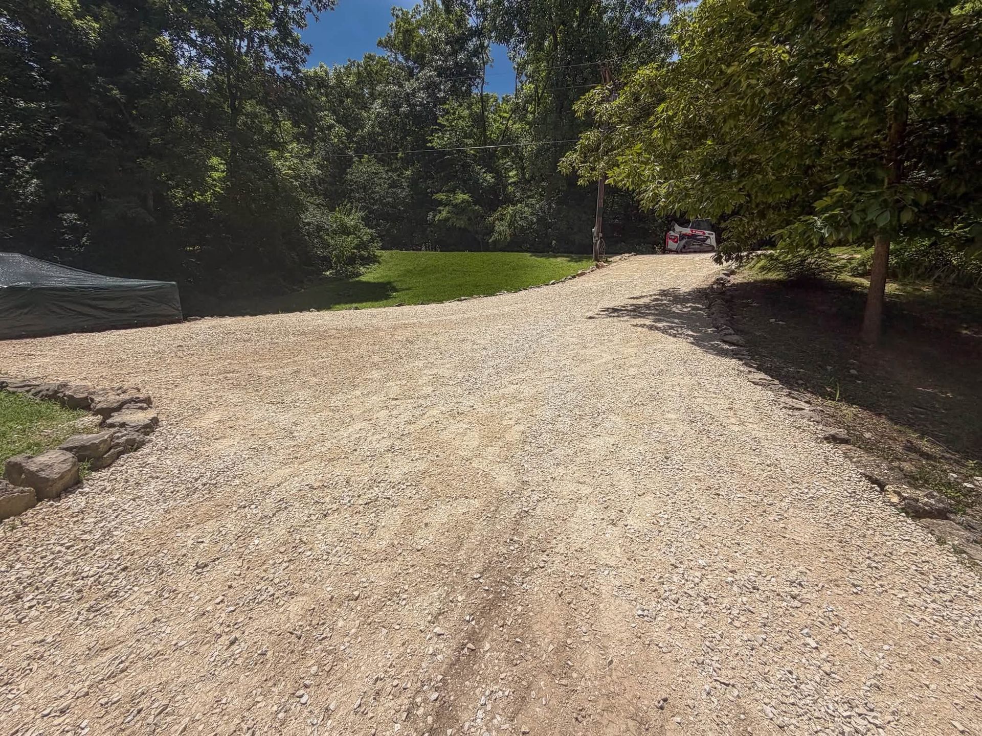 Gravel path curving through a sunlit green park with trees and bushes