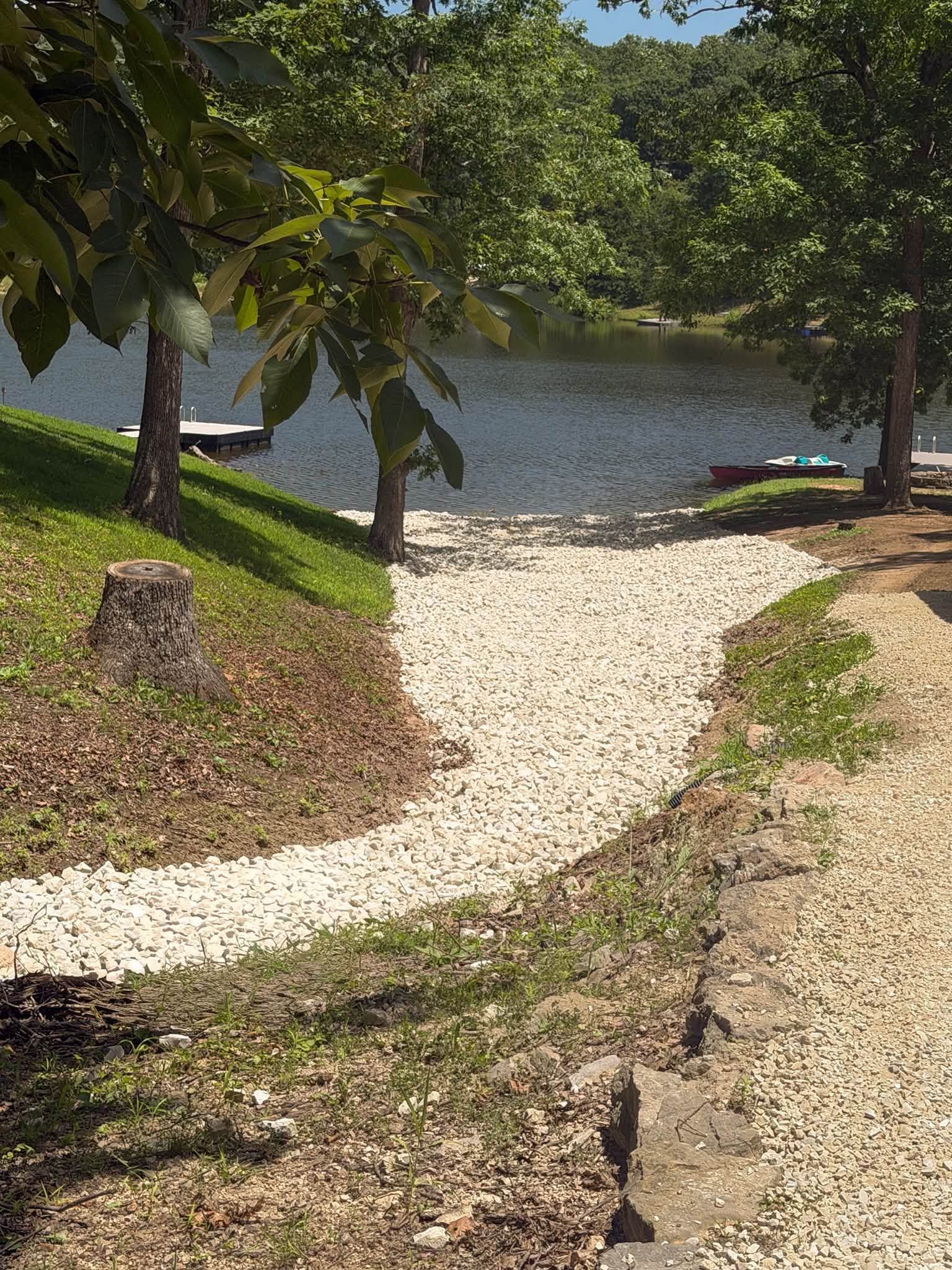 Stone path leading through grassy trees to a lake shore