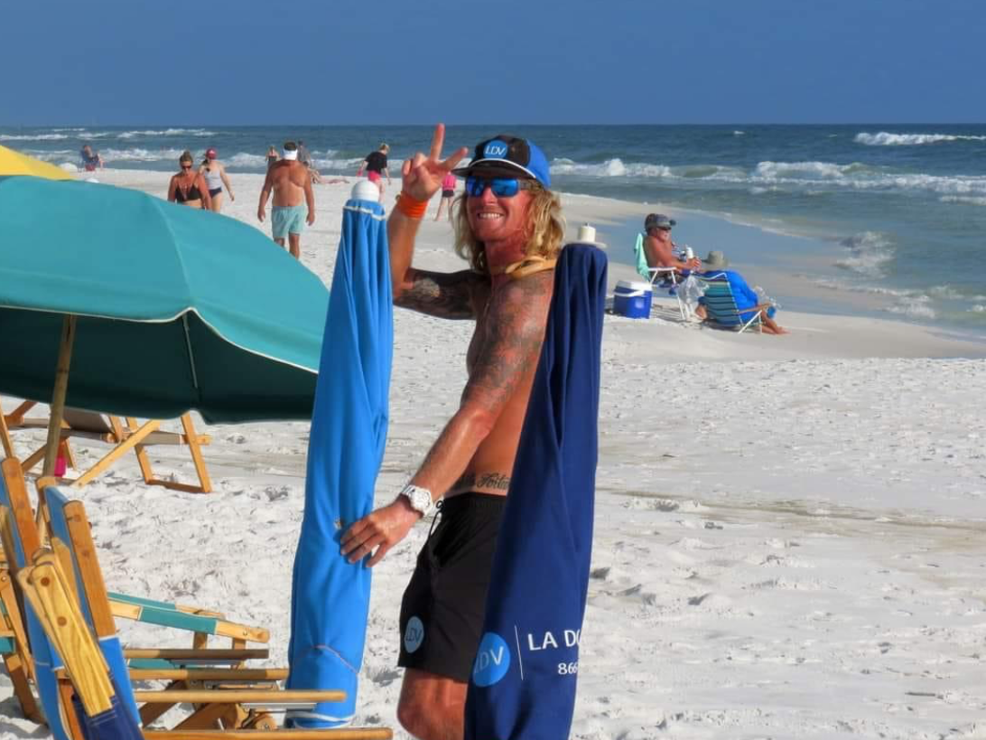 A man is standing on a beach holding an umbrella.