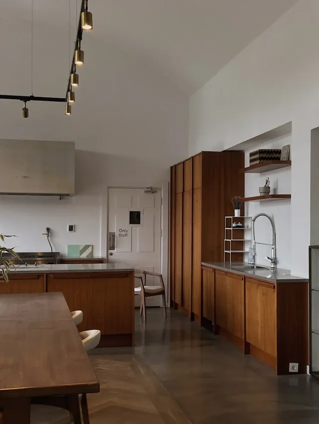 Modern kitchen with wood cabinets, stainless steel appliances, and a dining table.