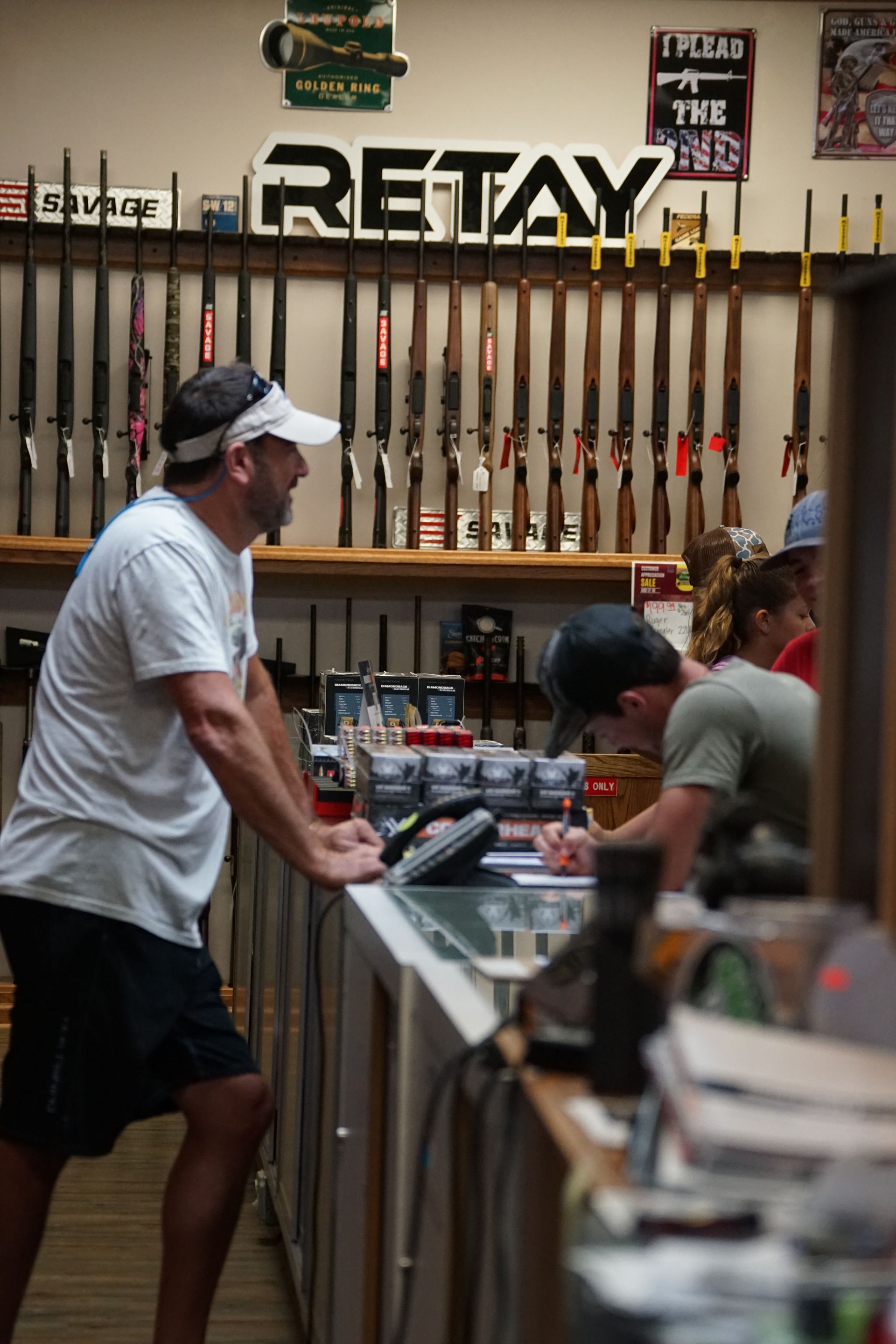 People chatting in a sports store with tennis rackets displayed on the wall.