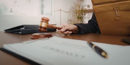 Courtroom desk with gavel, document, and pen beside a closed briefcase.