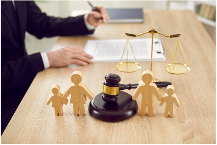 A man is sitting at a table with a gavel and scales of justice.
