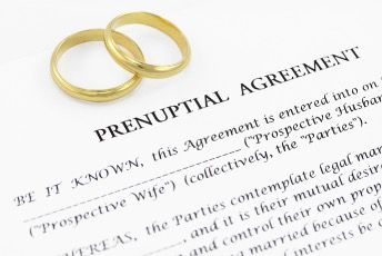 Gold wedding rings on a prenuptial agreement document