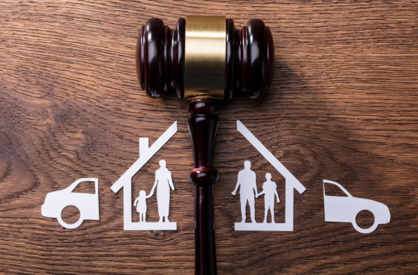 A wooden gavel with a family, house, and car cut around it.