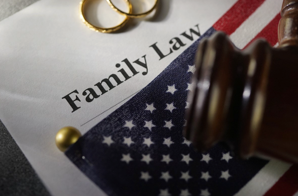 The words family law are on a piece of paper with an American flag, gavel, and wedding rings.