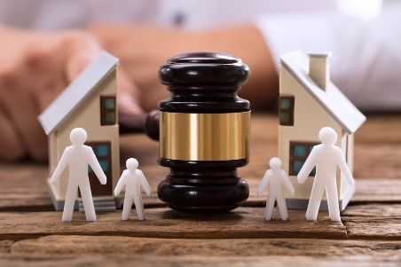 Divorce concept with gavel, model houses, stick figure family, and split.