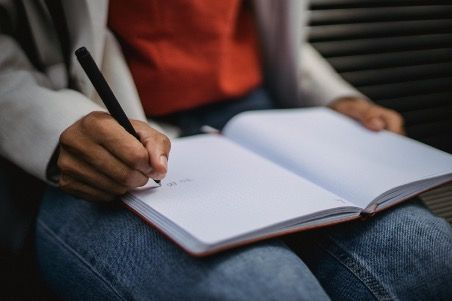 a man writing on a journal on his lap