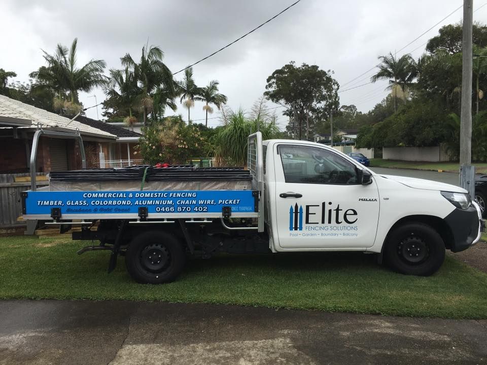 White Elite service pickup truck with blue flatbed parked on a residential street.