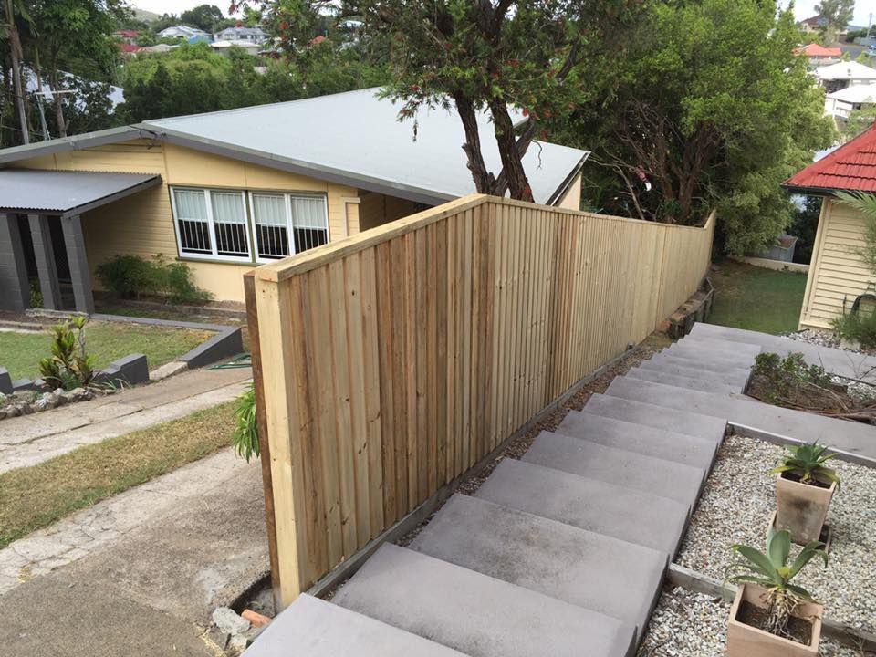 Long wooden fence beside a sloped concrete driveway in a residential neighborhood