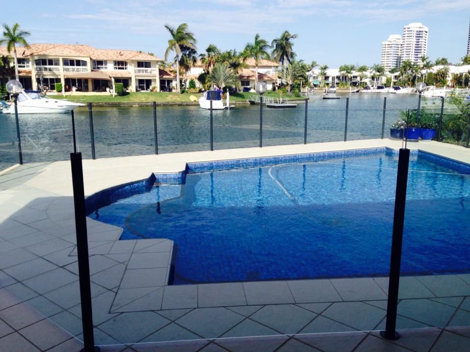 Poolside view of a canal with waterfront homes, palm trees, and blue sky