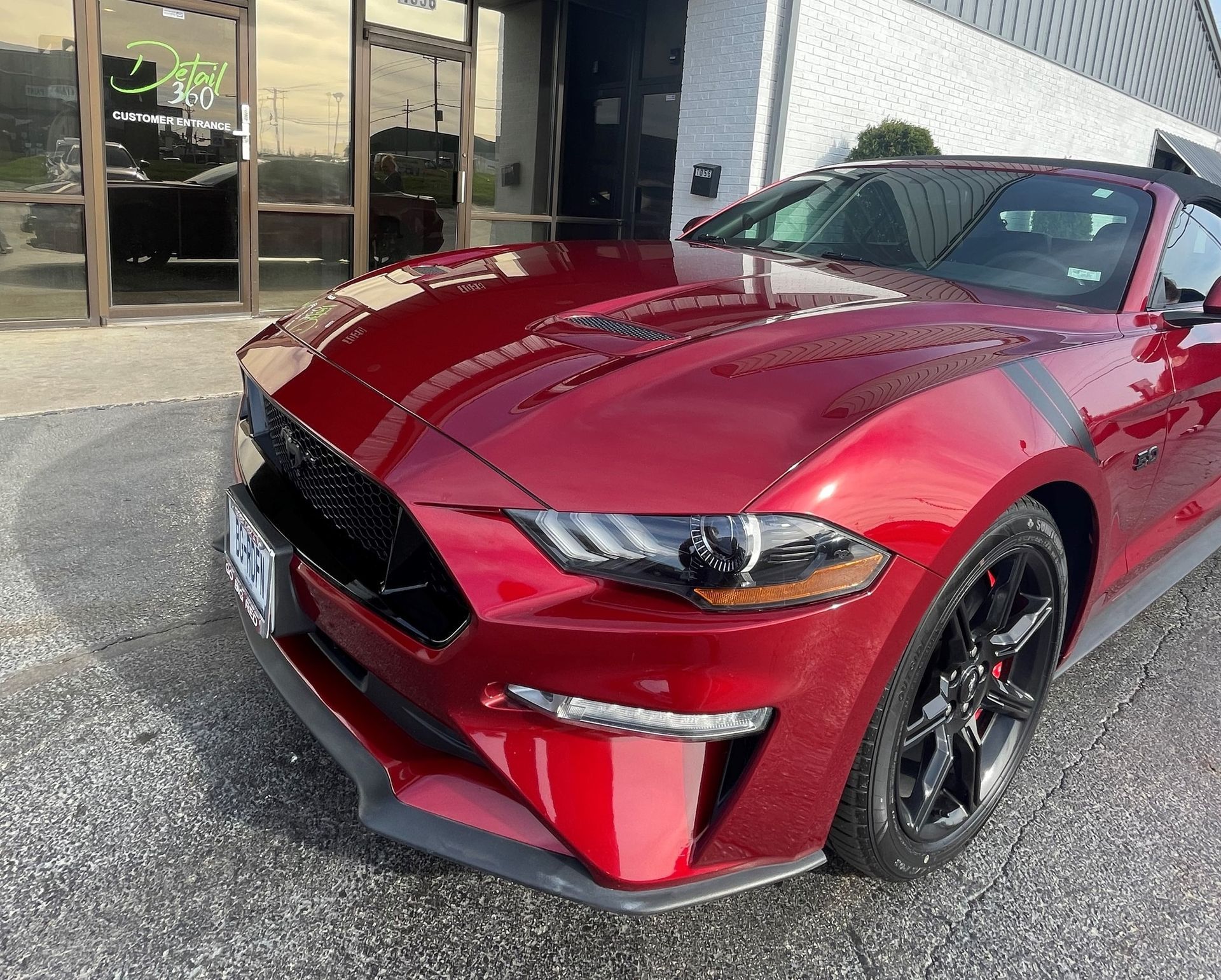 A red ford mustang is parked in front of a building.