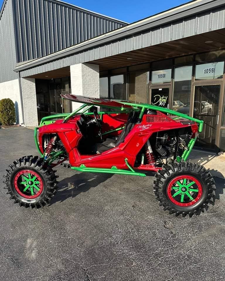 A red and green atv is parked in front of a building.