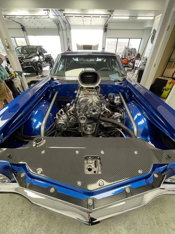 A blue car with a big engine is sitting in a garage.