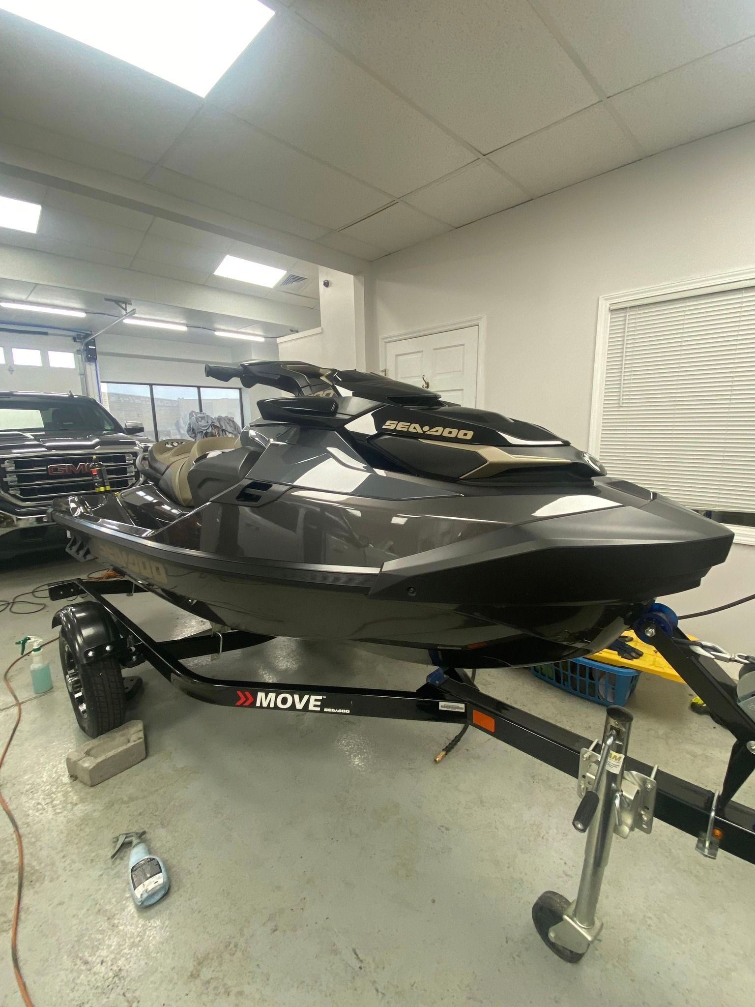 Jet ski on a trailer inside a building. Black and grey watercraft with a trailer hitch.