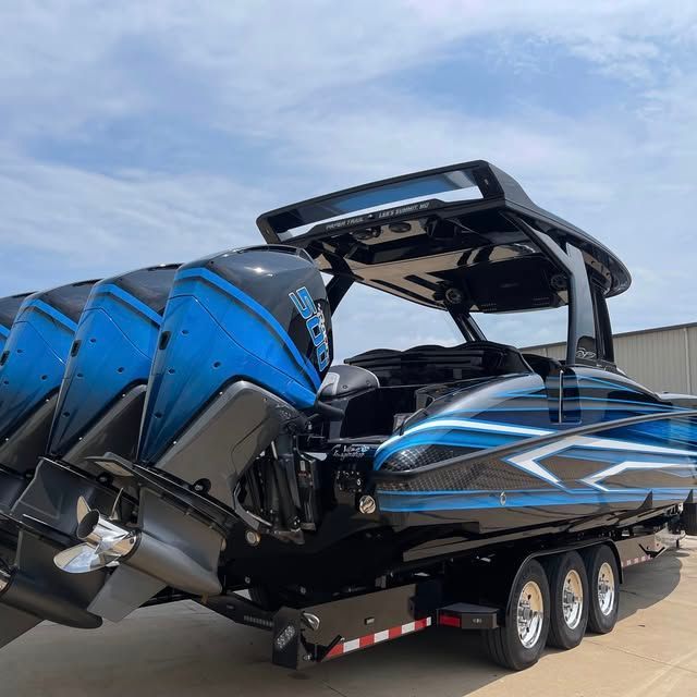 A black and blue boat is parked on a trailer in front of a building.