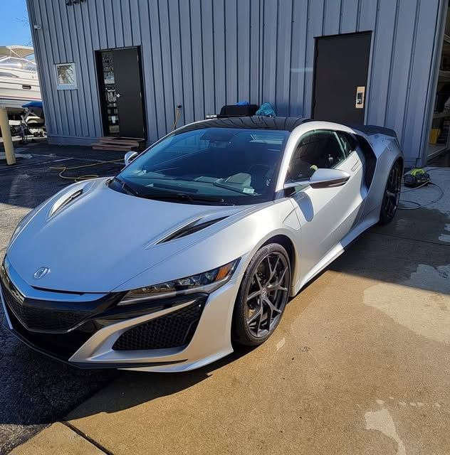 Silver Acura NSX sports car parked outside a building.