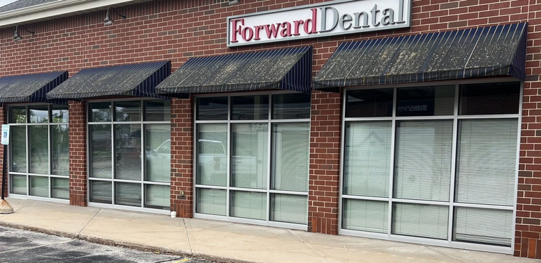 Forward Dental storefront with brick facade, large windows, and striped awnings.