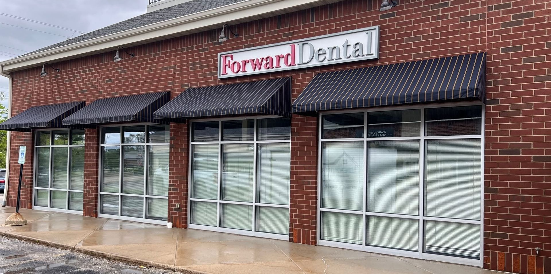 Brick storefront for Harvard Dental with striped awnings and large front windows