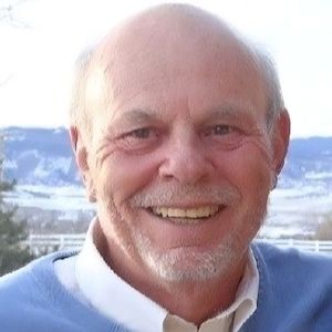 A man with a beard and a blue sweater is smiling for the camera.