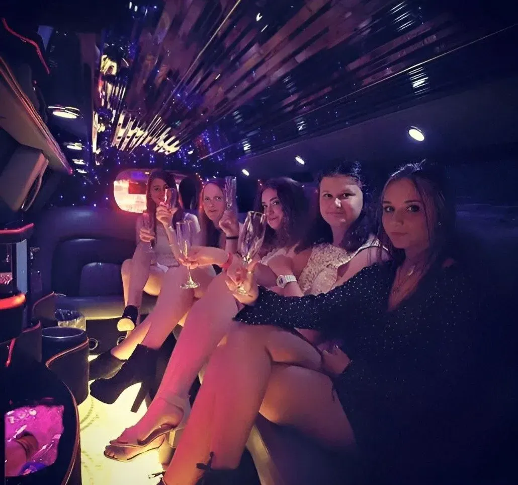 A Group of Women Are Sitting in a Limousine Holding Champagne Glasses — Superstretch300 Limousines in Sunshine Coast, QLD
