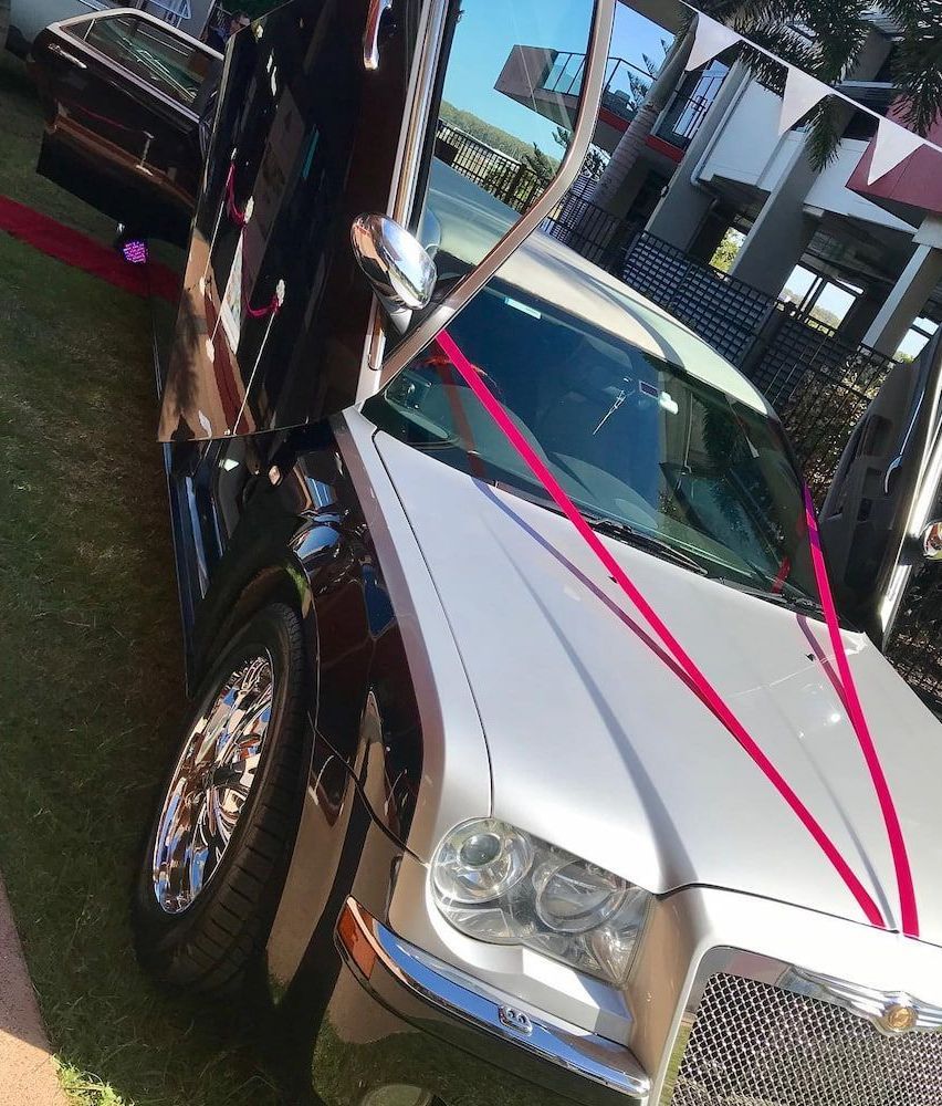 A Black and White Car With Red Ribbons on It — Superstretch300 Limousines in Sunshine Coast, QLD