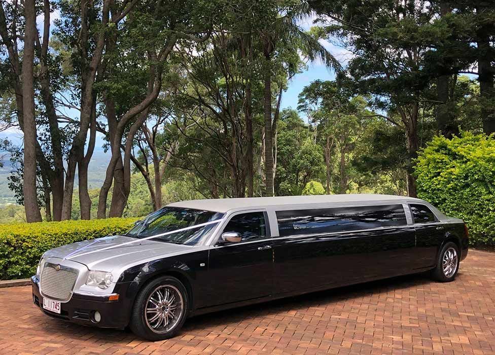 A Black Limousine is Parked on a Brick Driveway in Front of Trees — Superstretch300 Limousines in Sunshine Coast, QLD