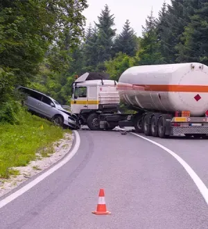 A car has crashed into a tanker truck on the side of the road.