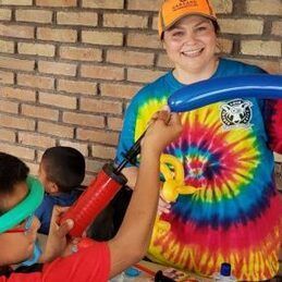 Lori serving at a childrens orphanage blowing up balloon animals