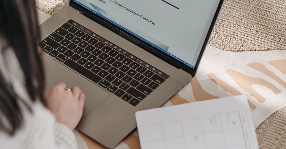 Traveler reviewing notes beside a laptop while planning a trip