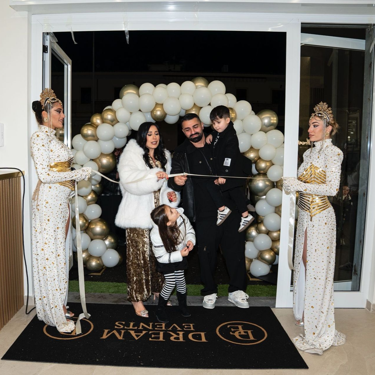 Una famiglia taglia il nastro durante la grande inaugurazione di Dream Events, con uno sfondo di un arco di palloncini.